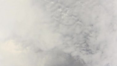 Düşük gri bulutlar hareket ederek berrak gri gökyüzünün alanını boşaltıyor. Geniş açılı lensüzerinde atmosferik olayların daha hızlı video kaydı.