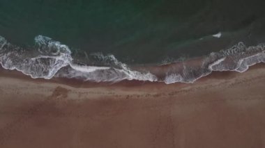 Kumlu sahil şeridinde dalgalanan turistik deniz dalgaları hiç bitmeyen güzel ve pürüzsüz görüntüler.