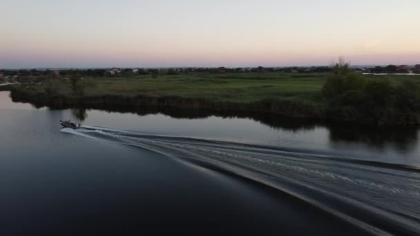 モーターボートが夜の川の眺めに沿って無人機から帆を上げ — ストック動画