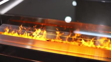 Elektrikli şöminedeki ateş camın arkasında yanıyor.