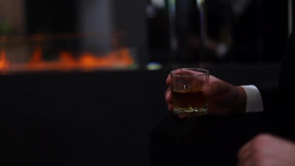 Üzletember a kandalló hátterében whiskyt iszik — Stock videók