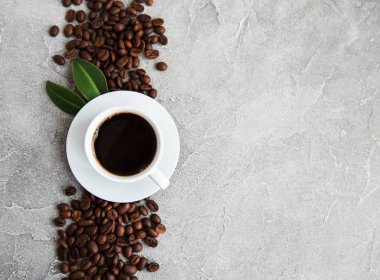 Bir fincan kahve ve kızarmış kahve çekirdeği.