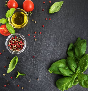 Yemek, zeytinyağı, Yeşil fesleğen, baharatlar ve siyah bir taş zemin üzerine domates için malzemeler