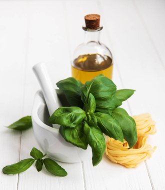 Taze yeşil fesleğen ve zeytinyağı bir beyaz ahşap tablo