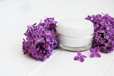 Eflatun çiçekler ve kozmetik krem beyaz ahşap zemin üzerinde