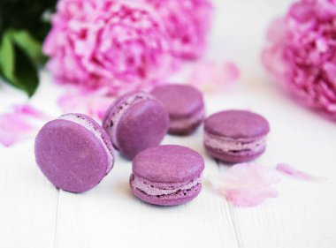 Beyaz ahşap bir masa üzerinde macarons ile pembe şakayık
