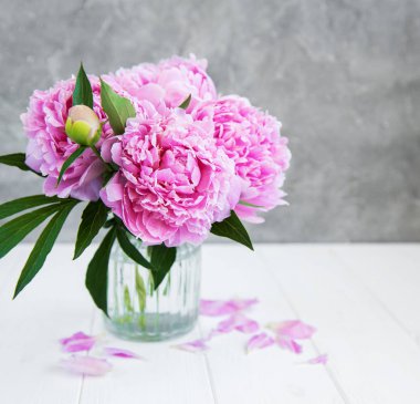 Beyaz ahşap bir masa üzerinde pembe şakayık çiçekli vazo