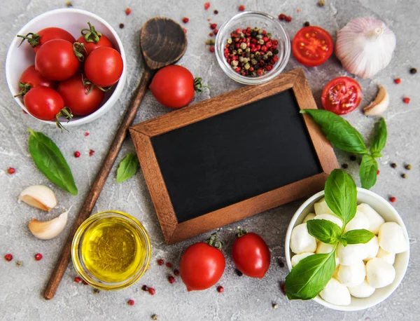 Italian food ingredients with blackboard on a stone background
