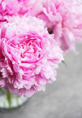 Bir taş zemin üzerine pembe şakayık çiçekli vazo