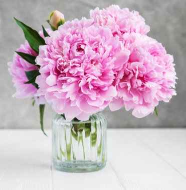 Beyaz ahşap bir masa üzerinde pembe şakayık çiçekli vazo