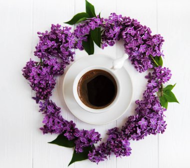 Bir beyaz tahta masaya kahve ve Lila çiçek fincan