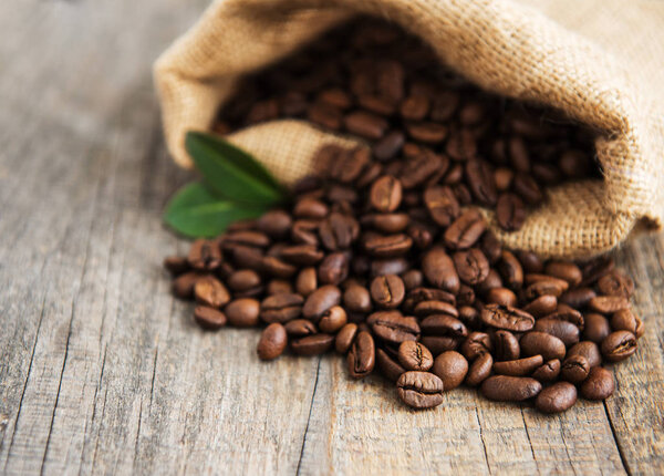 Roasted coffee beans in burlap bag on old table