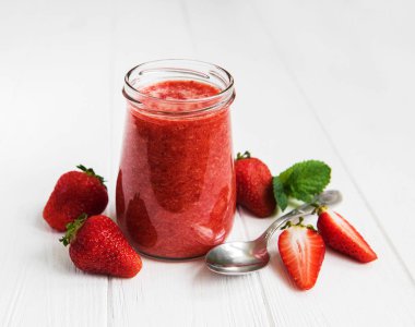 Beyaz ahşap bir masa üzerinde çilek güler yüzlü ile jar