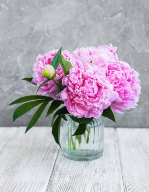 Beyaz ahşap bir masa üzerinde pembe şakayık çiçekli vazo