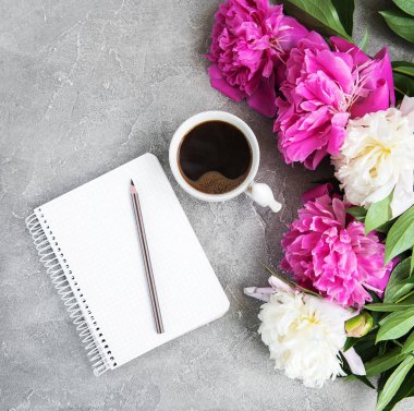 Eski bir taş zemin üzerine peonies ve kahve ile not defteri