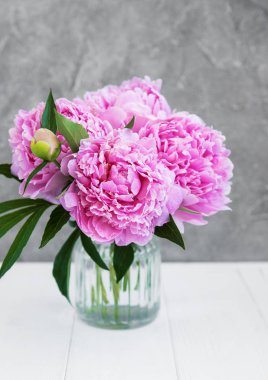 Beyaz ahşap bir masa üzerinde pembe şakayık çiçekli vazo