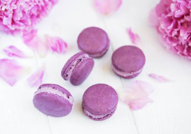 Beyaz ahşap bir masa üzerinde macarons ile pembe şakayık