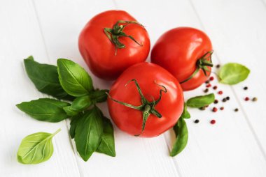 Beyaz ahşap bir masa üzerinde yeşil fesleğen ile taze domates