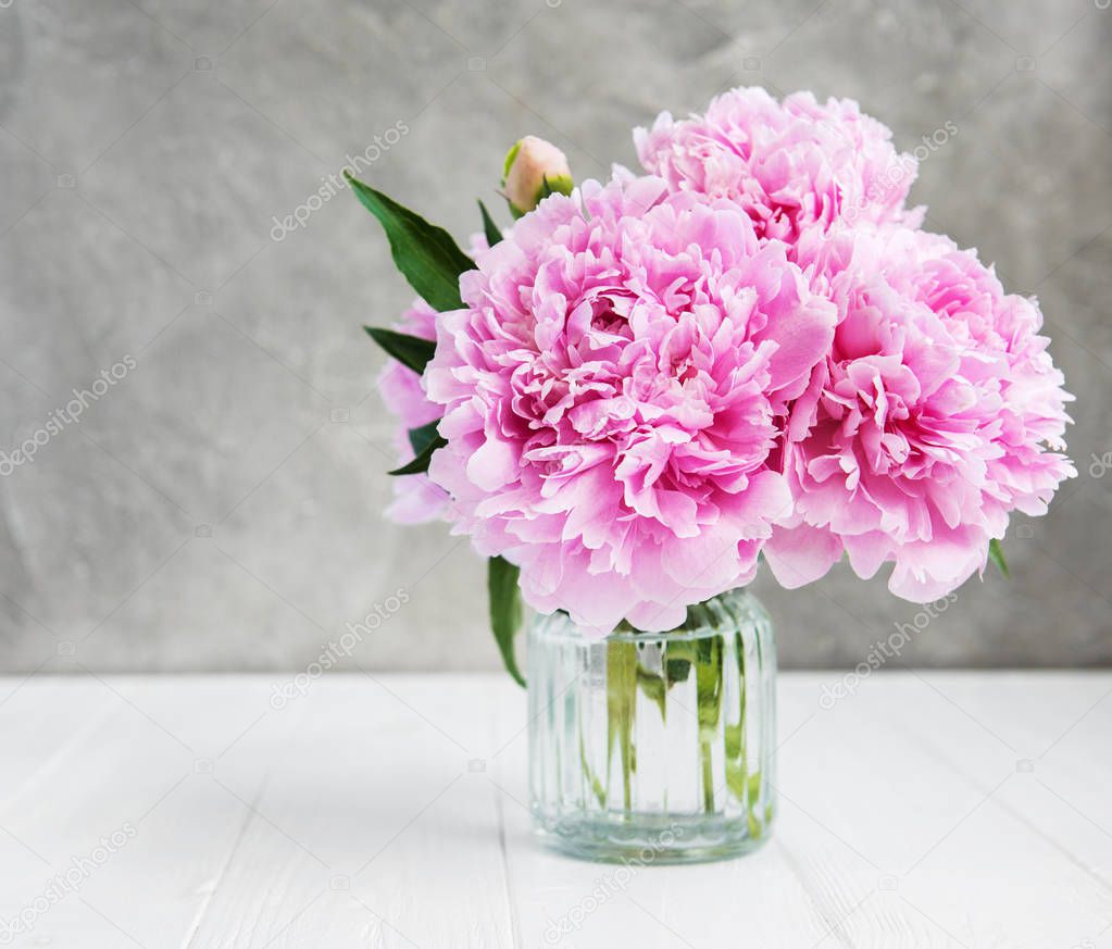 Vase with pink peony flowers on a white wooden table