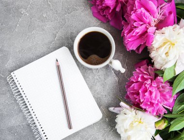 Eski bir taş zemin üzerine peonies ve kahve ile not defteri