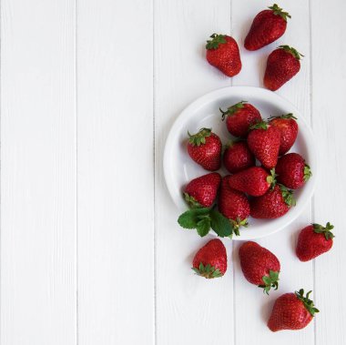Beyaz ahşap bir masa üzerinde taze çilek ile plaka