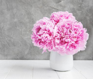 Beyaz ahşap bir masa üzerinde pembe şakayık çiçekli vazo