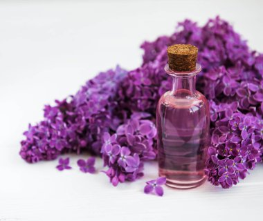 Beyaz ahşap zemin üzerinde eflatun çiçekli uçucu yağ