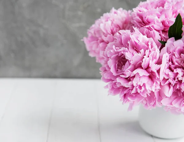 Beyaz ahşap bir masa üzerinde pembe şakayık çiçekli vazo