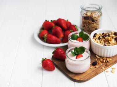 Sağlıklı Kahvaltı, yoğurt, taze çilek ve granola Beyaz ahşap bir masa üzerinde