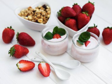 Sağlıklı Kahvaltı, yoğurt, taze çilek ve granola Beyaz ahşap bir masa üzerinde