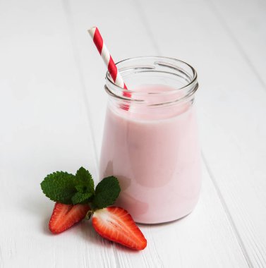 Beyaz ahşap bir masa üzerinde çilekli yoğurt ile jar