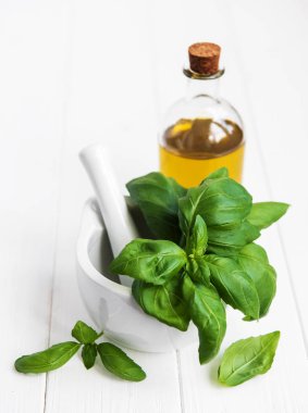 Taze yeşil fesleğen ve zeytinyağı bir beyaz ahşap tablo