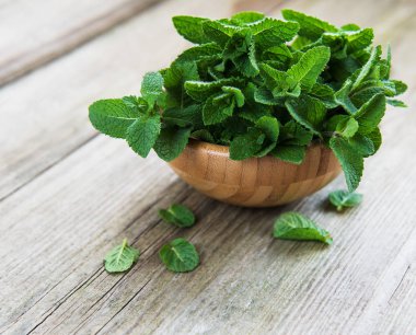 Eski ahşap arka plan üzerinde taze nane ile kase