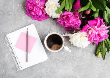 Eski bir taş zemin üzerine peonies ve kahve ile not defteri