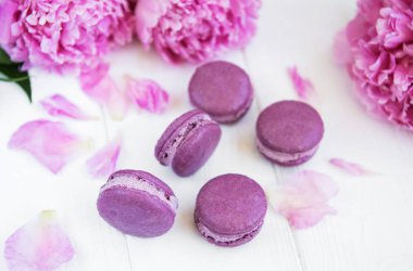 Beyaz ahşap bir masa üzerinde macarons ile pembe şakayık