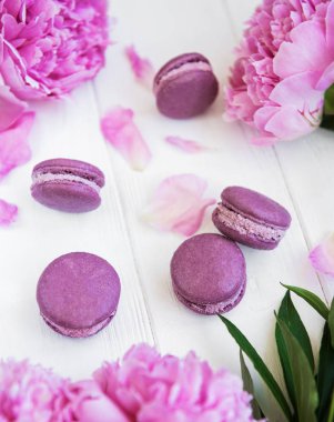 Beyaz ahşap bir masa üzerinde macarons ile pembe şakayık