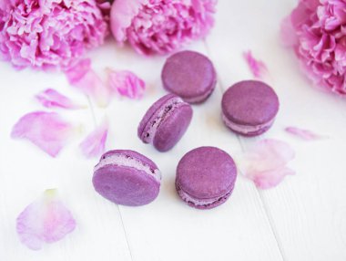 Beyaz ahşap bir masa üzerinde macarons ile pembe şakayık