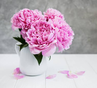 Beyaz ahşap bir masa üzerinde pembe şakayık çiçekli vazo