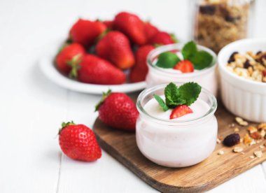 Sağlıklı Kahvaltı, yoğurt, taze çilek ve granola Beyaz ahşap bir masa üzerinde