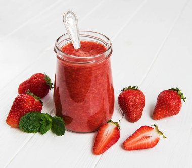 Beyaz ahşap bir masa üzerinde çilek güler yüzlü ile jar