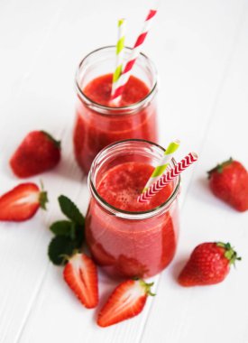 Beyaz ahşap bir masa üzerinde çilek güler yüzlü ile kavanoz