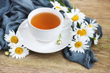 Eski ahşap bir masa üzerinde papatya çiçeği ile bitkisel çay