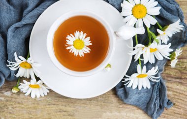 Eski ahşap bir masa üzerinde papatya çiçeği ile bitkisel çay