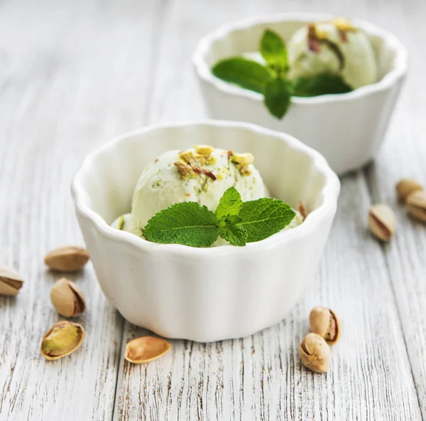 pistachio ice cream and mint with pistachio nuts on a old wooden background