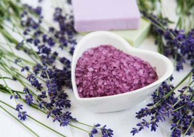 Deniz tuzu, sabun ve taze lavanta çiçekleri beyaz bir arka plan üzerinde kalp şeklinde bir kase