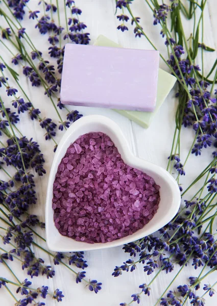 Deniz tuzu, sabun ve taze lavanta çiçekleri beyaz bir arka plan üzerinde kalp şeklinde bir kase