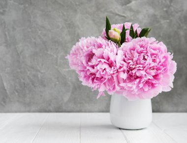 Beyaz ahşap bir masa üzerinde pembe şakayık çiçekli vazo