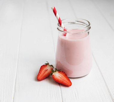 Beyaz ahşap bir masa üzerinde çilekli yoğurt ile jar