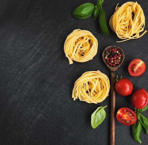 İtalyan gıda maddeleri. Makarna, domates, fesleğen ve siyah bir zemin üzerine baharat