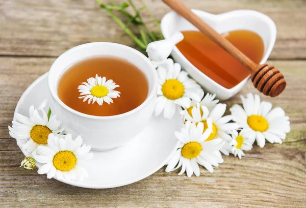 Eski ahşap bir masa üzerinde papatya çiçeği ile bitkisel çay